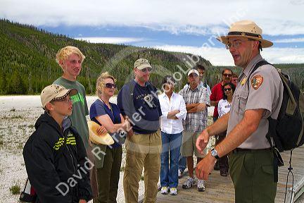 Park ranger giving a tour group information about the Upper Geyser Basin in Yellowstone National Park, Wyoming, USA.