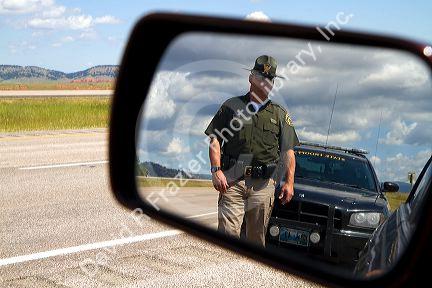 Wyoming Highway Patrol officer on seen in rear-view mirror along I-90 near the Wyoming, South Dakota border, USA. MR