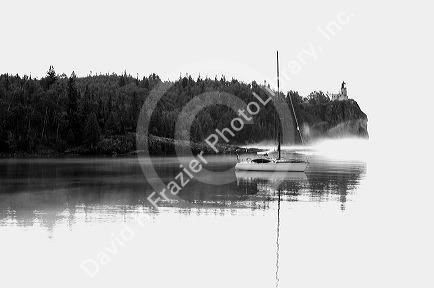 A morning view of Spilt Rock Lighthouse with sailboat and mist on Lake Superior, Minnesota, USA.