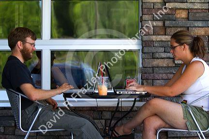 Modern couple using laptop personal computers at a coffee shop in Boise, Idaho, USA.