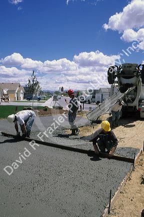 Workers pouring and screeding a concrete slab.