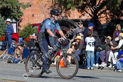 Police officer riding a bicycle at the Trailing of the Sheep Parade on Main Street in Ketchum, Idaho, USA.