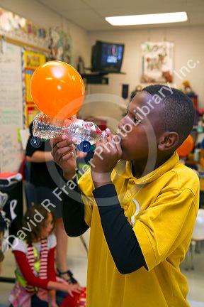 Student blowing up a balloon as part of a science experiment in a fourh grade classroom at a public elementary school in Brandon, Florida, USA.