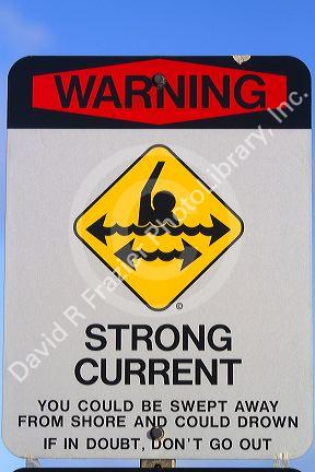 Beach sign warning of strong current and on the island of Kauai, Hawaii, USA.