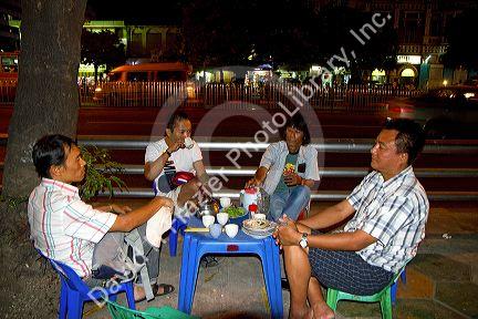 Burmese people eat and drink outdoors near the Sule Paya located in the heart of downtown (Rangoon) Yangon, (Burma) Myanmar.