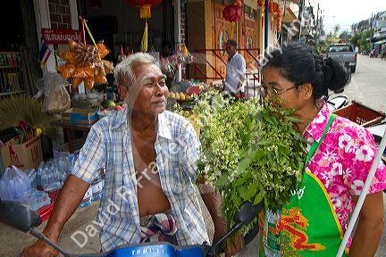 Grocer smelling fresh bay leaves being offered for sale by the grower on the island of Ko Samui, Thailand.
