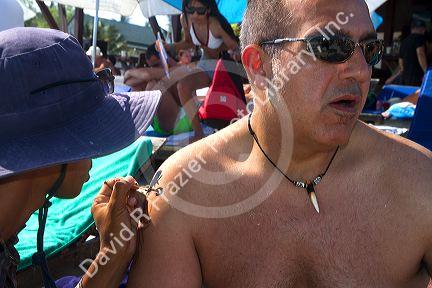 Man receiving a traditional tattoo at Chaweng beach on the island of Ko Samui, Thailand.