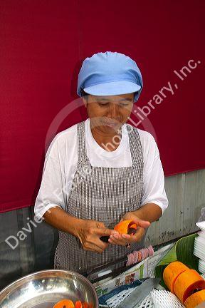 Street vendor cutting fresh fruit in Bangkok, Thailand.