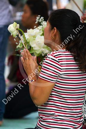 Woman praying at the Temple of the Emerald Buddha located within the precincts of the Grand Palace, Bangkok, Thailand.