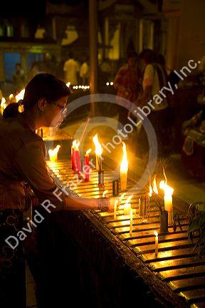 Woman lighting a candle at the Shwedagon Paya located in (Rangoon)Yangon, (Burma) Myanmar.
