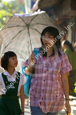 Burmese mother and daughter share the shade of an umbrella in (Rangoon) Yangon, (Burma) Myanmar.