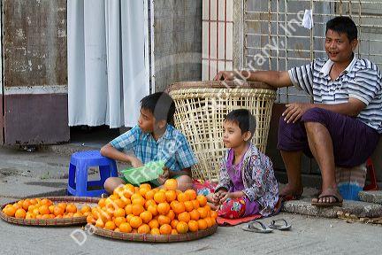 Burmese father and sons selling oranges on the street in (Rangoon) Yangon, (Burma) Myanmar.