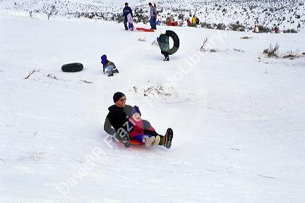 Grandfather sledding with his grandaughter in the snow.