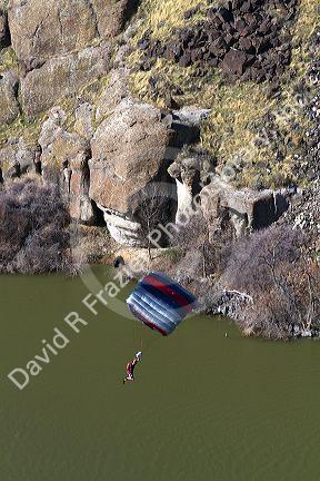A BASE jumper parachuting from the I.B. Perrine Bridge spanning the Snake River canyon at Twin Falls, Idaho, USA.