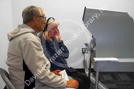 Visually impared woman using a headset for voting assistance at a polling station in Boise, Idaho, USA.