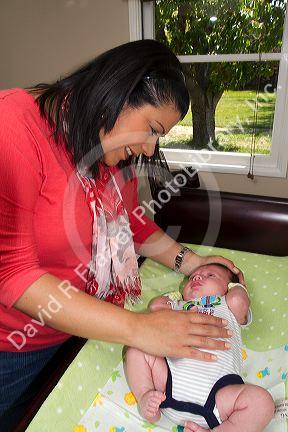 Hispanic mother with infant son on a changing table in Boise, Idaho, USA. MR