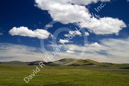 Cumulus clouds and blue sky over green fields near Pine, Idaho, USA.
