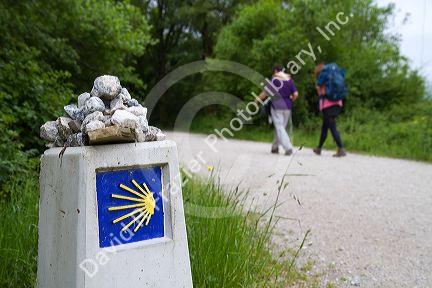 Pilgrims walk near a marker along the Camino De Santiago, the Way of St. James pilgrimage route, Navarra, Spain.
