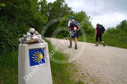 Pilgrims walk near a marker along the Camino De Santiago, the Way of St. James pilgrimage route, Navarra, Spain.