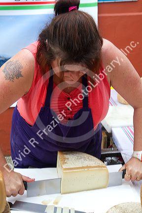 Basque woman slicing cheese at a Basque market at Saint-Jean-de-Luz in the Basque province of Labourd, southwestern France.