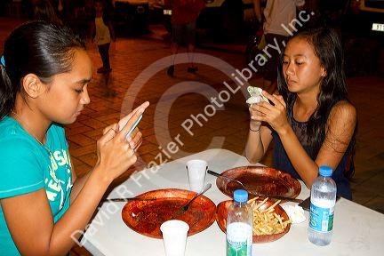 Tahitian teenage girls using cell phones on the island of Tahiti, French Polynesia.