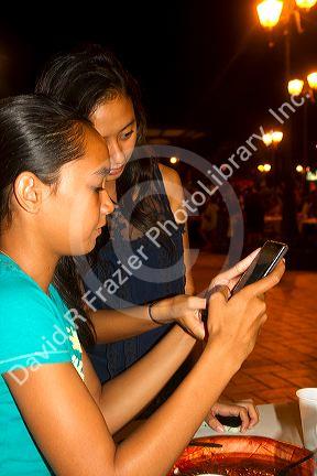 Tahitian teenage girls using cell phones on the island of Tahiti, French Polynesia.