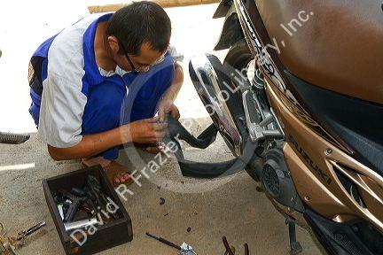 Sidewalk mechanic fixing a flat tire on a scooter in Da Lat, Vietnam.