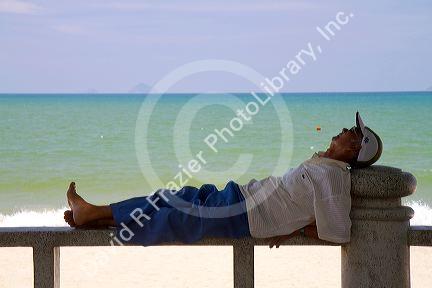 Man taking a nap on a bench at the beach in Nha Trang, Vietnam.