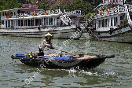 Woman rowing a small boat in Ha Long Bay, Vietnam.