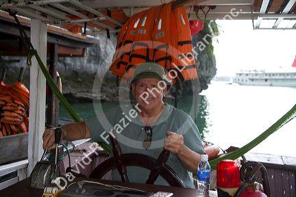 American tourist captoning a tour boat in Ha Long Bay, Vietnam.