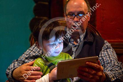 Man reading from an iPad tablet to a young boy in Boise, Idaho, USA.