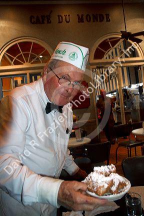 Waiter serving beignets at Cafe Du Monde in the French Quarter, New Orleans, Louisiana, USA.