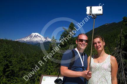 Tourists use a selfie stick to take a selfie with a smart phone at Mount Rainier in the state of Washington, USA.