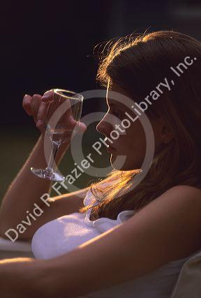 A woman sits with wine glass in hand. MR