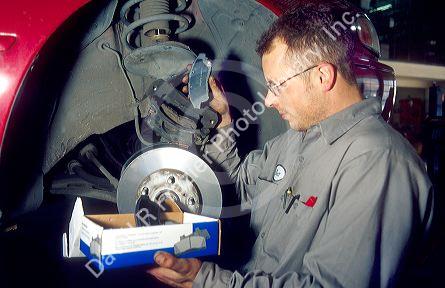 An auto mechanic inspecting and changing brake pads.