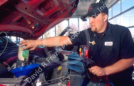A male adult  mechanic changing the oil in an automobile.