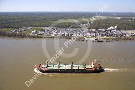 Bulk material cargo ship passing petro chemical refinery near New Orleans, Louisiana.