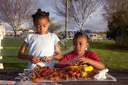 African american girls eating crawfish and corn on the cob in New Orleans, Louisiana.
