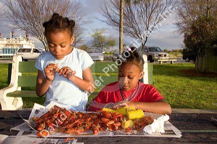 African american girls eating crawfish and corn on the cob in New Orleans, Louisiana.
