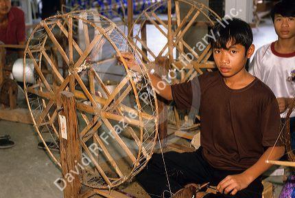 A boy makes silk thread in Thailand.