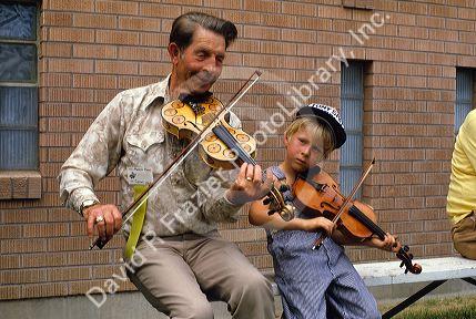 Manny Shaw plays the fiddle with a young boy at the Fiddle Festival in Weiser, Idaho.