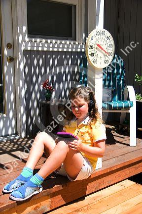 Nine year old girl listening to a walkman, personal cd player in 100 degree weather.