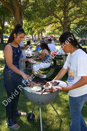 Hispanic women having barbecue at a picnic in the park. Sandy Point near Boise, Idaho.