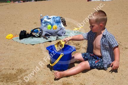 Young boy playing with a shovel and pale at the beach. Sandy Point near Boise, Idaho.