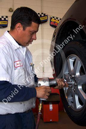 Installing tire on automobile. Mechanic uses impact air wrench.