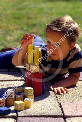 A boy concentrates while playing with building blocks.