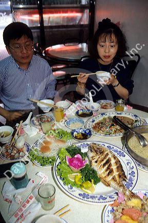 Chinese people eating a meal in a restaurant, Taiwan.  Woman has surprised look on her face.