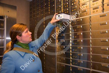 Woman reaching for a safe deposit box.