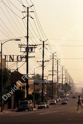 A Los Angeles street lined with cars and electric power lines, California.