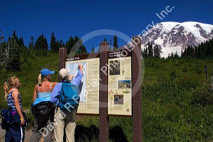 Hikers look at map of Mt. Rainier in Mt. Rainier National Park, Washington.